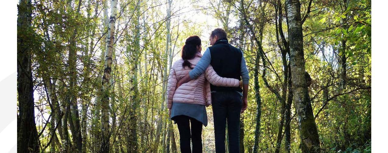 Couple away walking arm in arm on a path in the woods